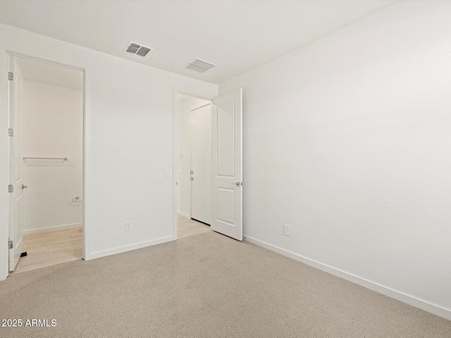 unfurnished bedroom featuring visible vents, light carpet, and baseboards