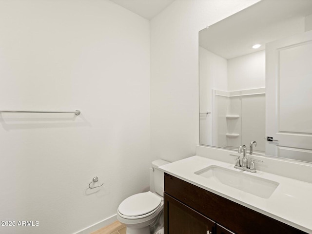 bathroom featuring baseboards, vanity, and toilet