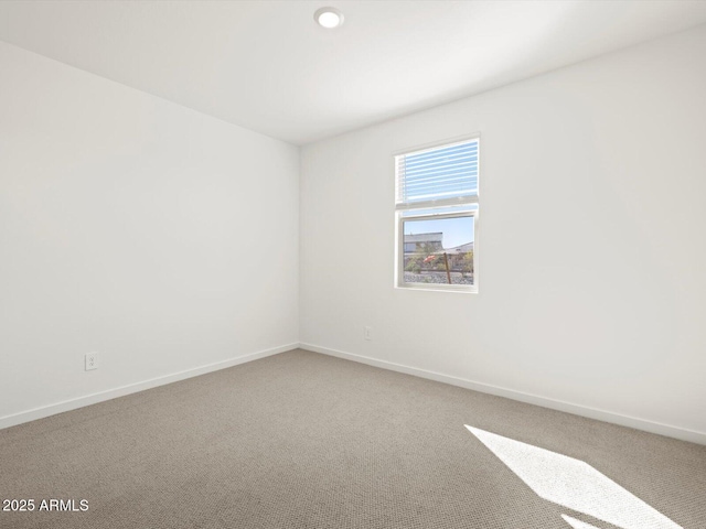 carpeted spare room featuring baseboards