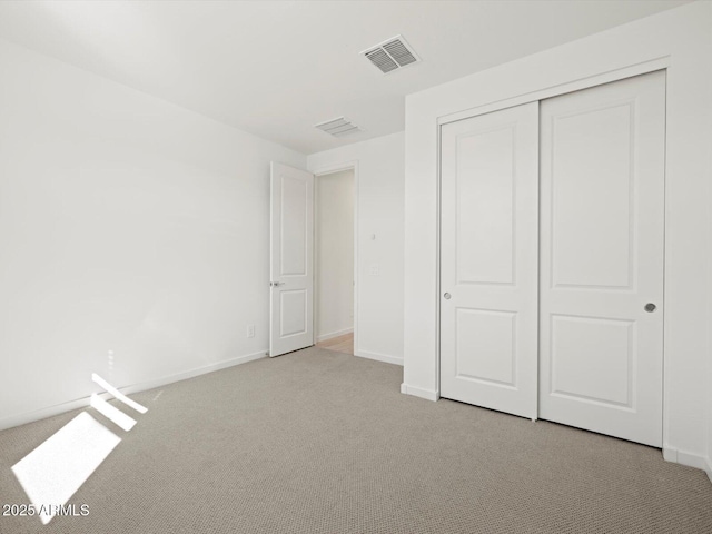 unfurnished bedroom featuring carpet, a closet, visible vents, and baseboards