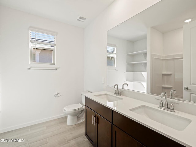 bathroom featuring toilet, a sink, baseboards, and wood finished floors