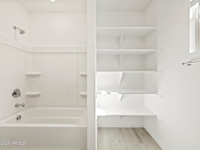 bathroom featuring wood tiled floor, baseboards, and bathing tub / shower combination