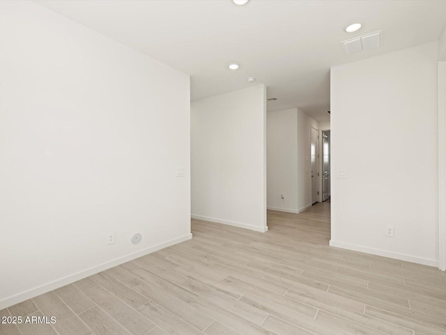 unfurnished room featuring light wood-type flooring, visible vents, and baseboards