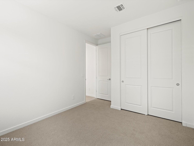 unfurnished bedroom featuring baseboards, a closet, visible vents, and carpet flooring