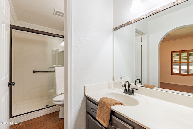 bathroom featuring hardwood / wood-style floors, vanity, a shower with door, crown molding, and toilet