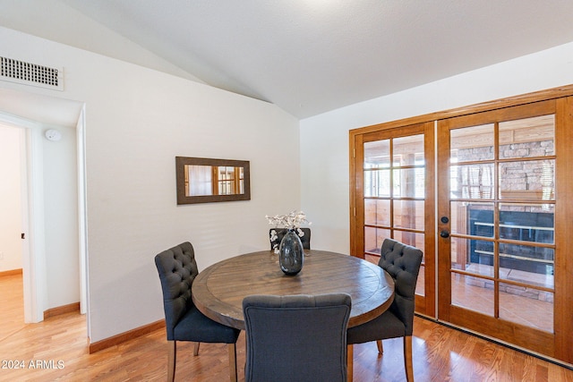 dining area with french doors, light hardwood / wood-style floors, and vaulted ceiling