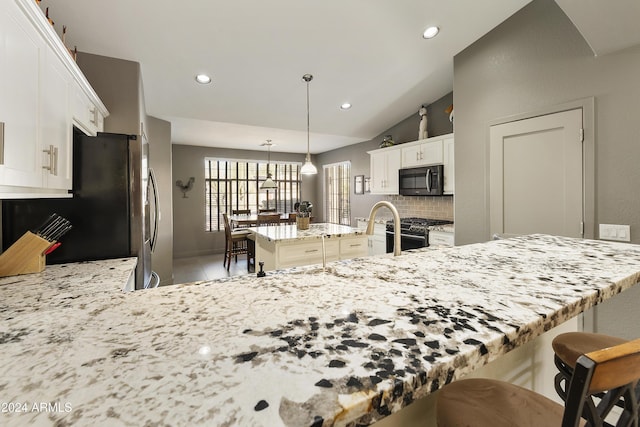 kitchen with pendant lighting, a center island, stainless steel appliances, decorative backsplash, and vaulted ceiling