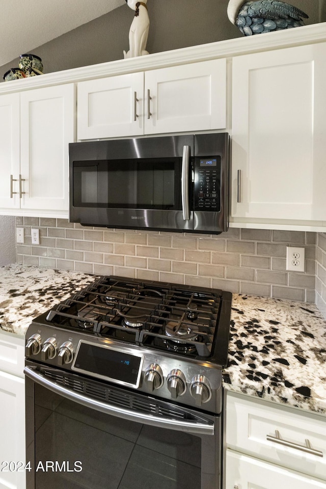 kitchen featuring vaulted ceiling, white cabinetry, stainless steel appliances, and tasteful backsplash