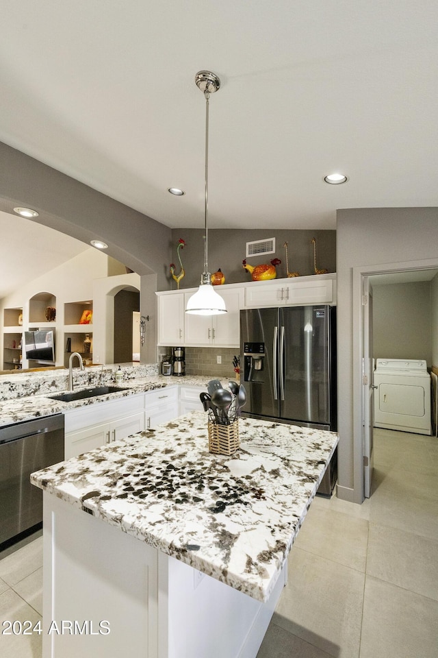 kitchen with decorative light fixtures, washer / dryer, sink, stainless steel appliances, and white cabinets