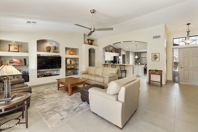 living room featuring ceiling fan, built in features, and lofted ceiling