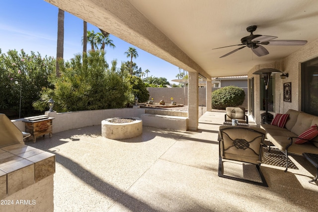 view of patio with ceiling fan and an outdoor living space with a fire pit