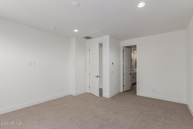 unfurnished bedroom featuring light colored carpet and ensuite bathroom