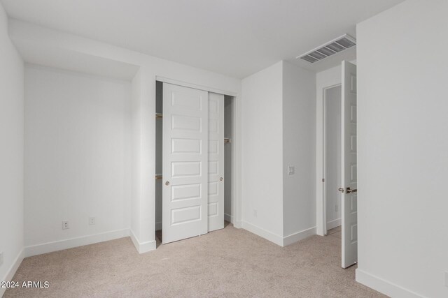 unfurnished bedroom featuring light colored carpet and a closet