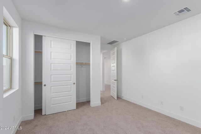 unfurnished bedroom with a closet and light carpet