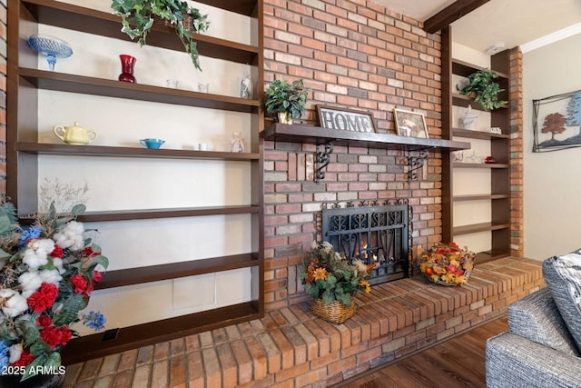 living room with dark wood-type flooring, a brick fireplace, and beamed ceiling