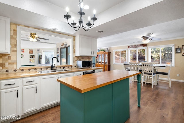 kitchen featuring white cabinetry, butcher block counters, sink, hanging light fixtures, and a center island