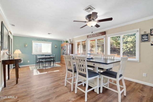 dining space with crown molding, ceiling fan, and light wood-type flooring