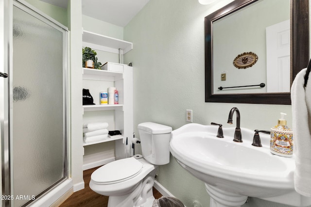 bathroom featuring toilet, sink, hardwood / wood-style floors, and a shower with shower door