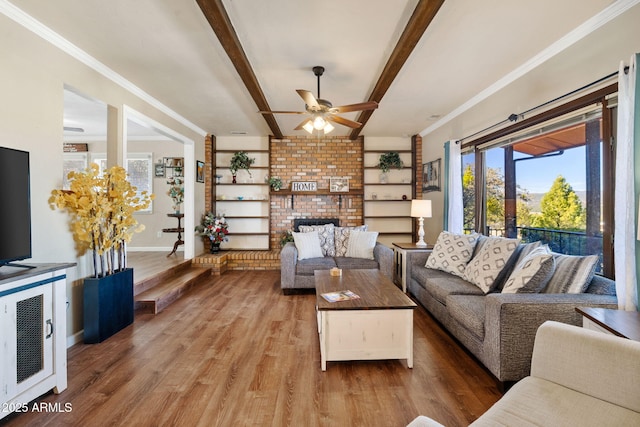 living room with hardwood / wood-style flooring, ornamental molding, a brick fireplace, and beam ceiling