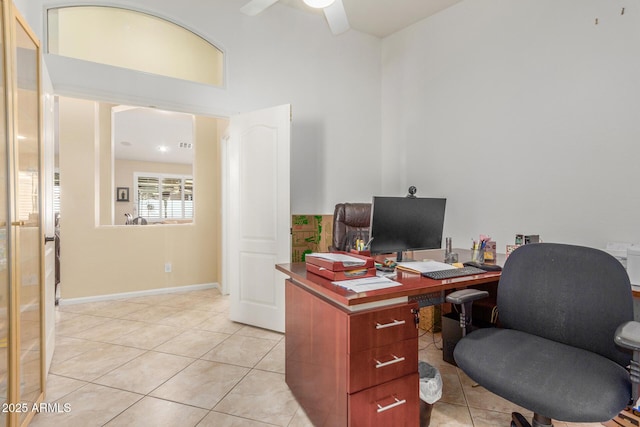 office space featuring light tile patterned floors, baseboards, ceiling fan, and a towering ceiling