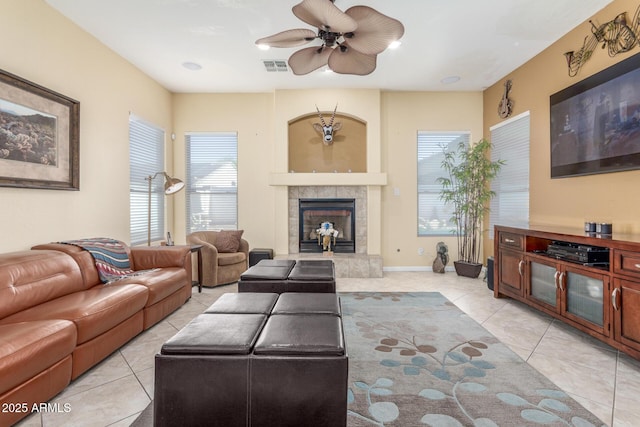 living room featuring light tile patterned floors, a fireplace, visible vents, and a ceiling fan