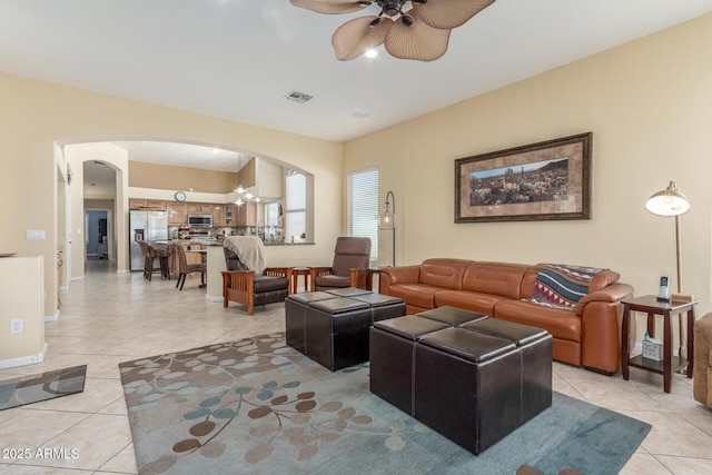 living area with ceiling fan, light tile patterned flooring, arched walkways, and visible vents