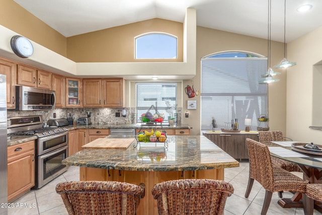 kitchen featuring glass insert cabinets, stainless steel appliances, light tile patterned flooring, and dark stone countertops