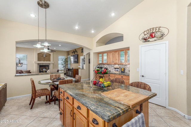 kitchen with a fireplace, baseboards, glass insert cabinets, and light tile patterned floors