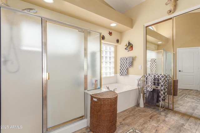 bathroom featuring a bath, wood finished floors, a stall shower, and recessed lighting