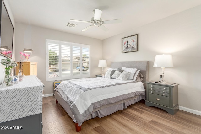 bedroom featuring baseboards, a ceiling fan, visible vents, and light wood-style floors