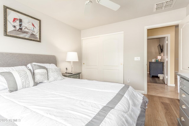 bedroom featuring a ceiling fan, a closet, visible vents, and wood finished floors