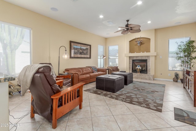 living area with a fireplace, a wealth of natural light, a ceiling fan, and light tile patterned floors