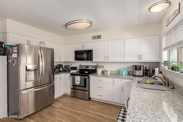 3447 E Dolphin Ave, Mesa, AZ 85204 - kitchen with appliances with stainless steel finishes, white cabinets, light stone counters, and light wood-style floors