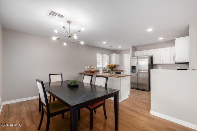 dining room with sink, a chandelier, and light hardwood / wood-style flooring