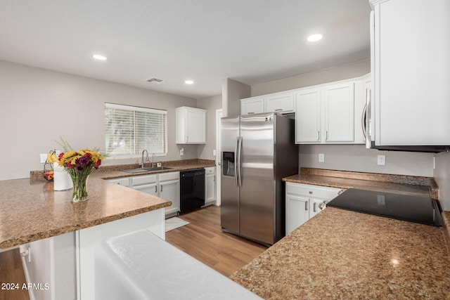 kitchen with black appliances, sink, light wood-type flooring, and white cabinetry