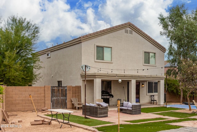 rear view of property with an outdoor living space and a patio area