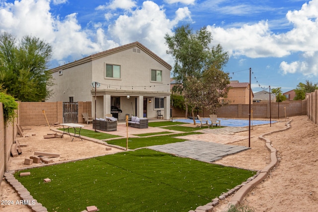 back of property with outdoor lounge area, a swimming pool, a patio, and a lawn