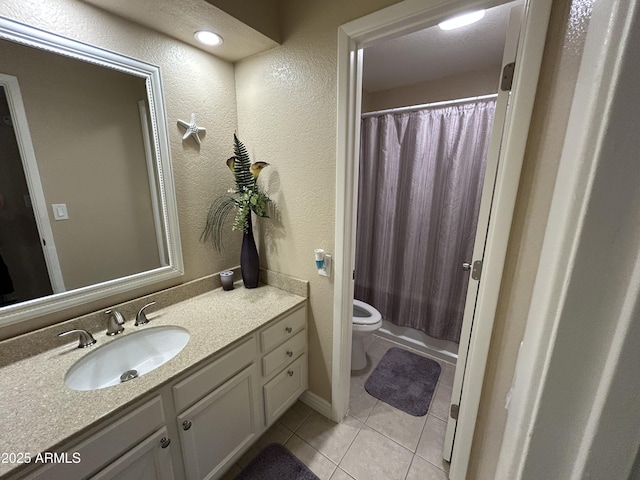 bathroom with vanity, tile patterned flooring, a textured wall, and toilet