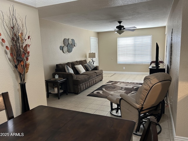 living room featuring light tile patterned floors, a textured wall, and a ceiling fan