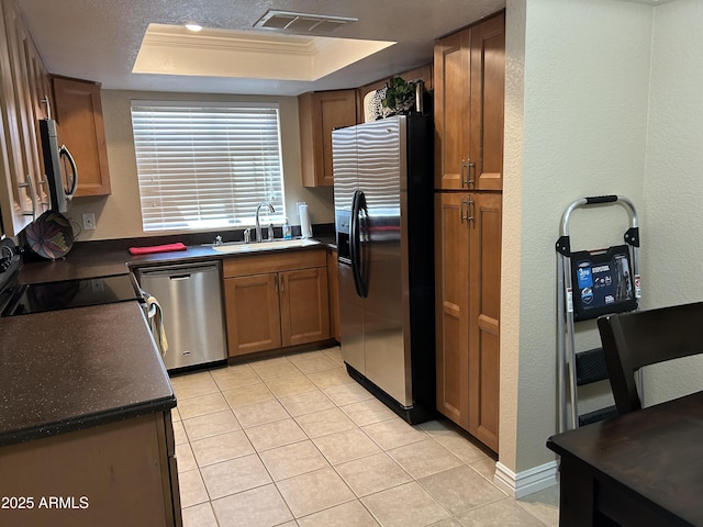kitchen featuring visible vents, dark countertops, a tray ceiling, a sink, and stainless steel appliances