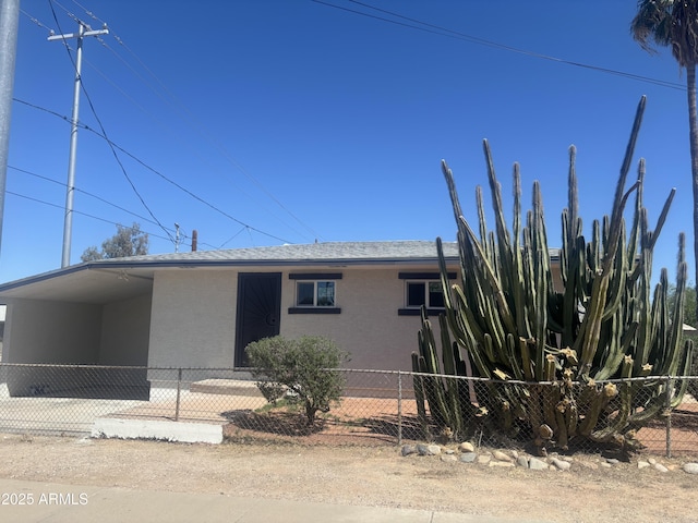 view of front facade with fence private yard, stucco siding, and a carport
