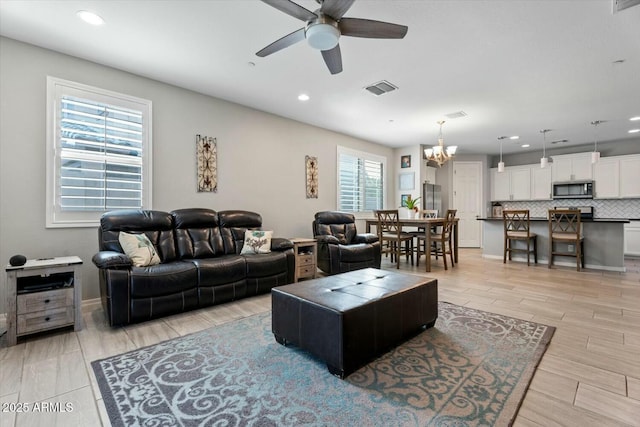 living area featuring visible vents, baseboards, wood tiled floor, ceiling fan with notable chandelier, and recessed lighting