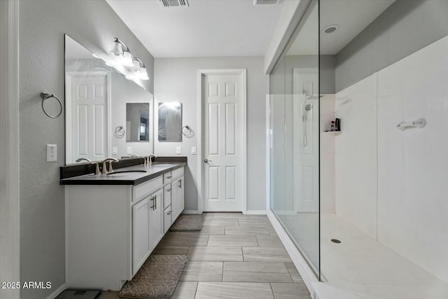 full bath with double vanity, walk in shower, a sink, and visible vents