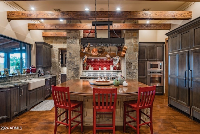 interior space with dark hardwood / wood-style flooring, dark stone counters, appliances with stainless steel finishes, dark brown cabinets, and backsplash