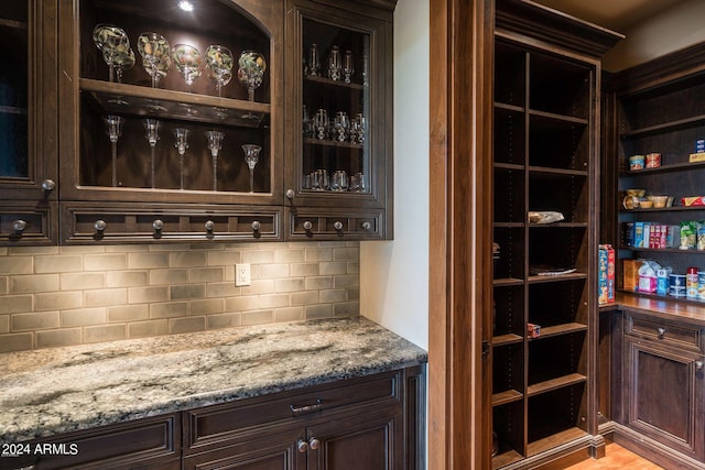 bar with dark brown cabinets and tasteful backsplash