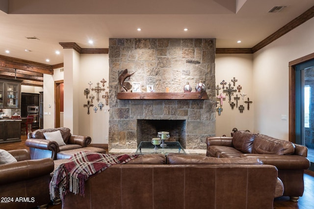 living room with ornamental molding, dark hardwood / wood-style flooring, and a stone fireplace