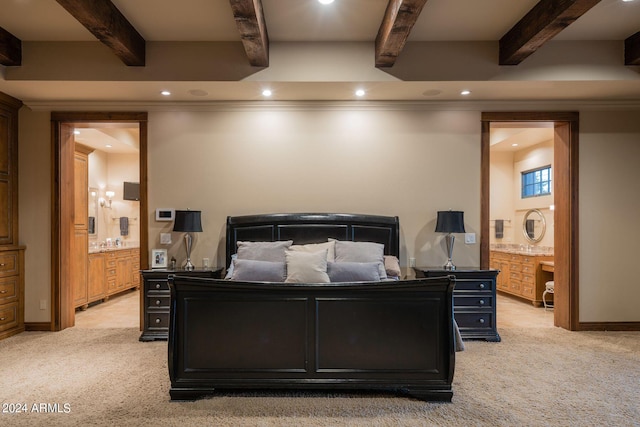 bedroom with beam ceiling, ensuite bathroom, and light carpet