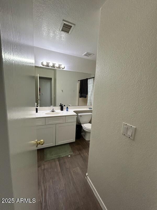 7664 W Vermont Ave, Glendale, AZ 85303 - bathroom with wood finished floors, toilet, vanity, a textured wall, and a textured ceiling