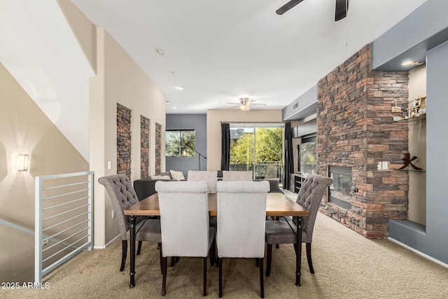 dining room with carpet, a stone fireplace, and ceiling fan