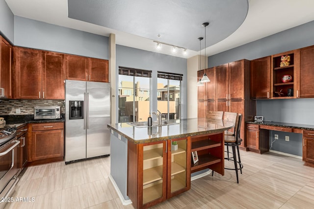 kitchen featuring built in desk, pendant lighting, sink, backsplash, and stainless steel appliances